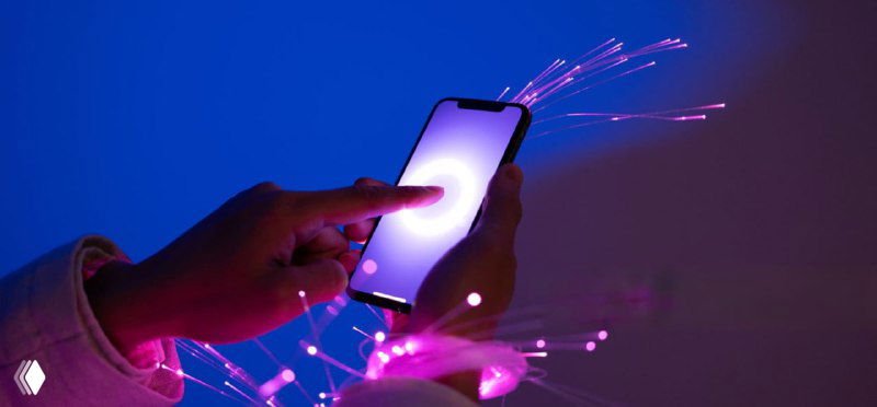 Рука держит смартфон на неоновом синем фоне; вокруг расходятся фиолетовые оптические волокна — визуал цифровой связи и нейросетей.