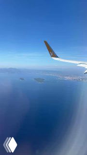 Вид из окна самолёта на глубокое синее Лазурное море с маленькими островами, в кадре видно крыло самолёта — кадр автора в пути на Лазурный берег.