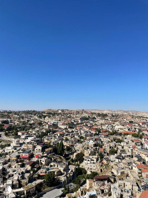 Панорамный вид на город и холмы с высоты; множество домов и куполообразных формаций, ясное голубое небо — пейзаж путешествия и осмотра достопримечательностей.
