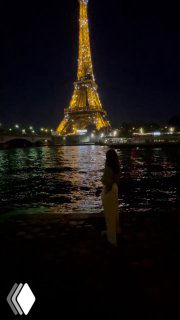 Подсвеченная Эйфелева башня ночью и река Сена на заднем плане; на переднем плане силуэт человека у воды и отражения огней.