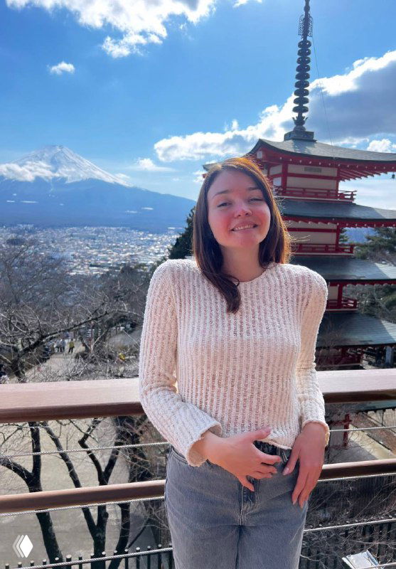 Женщина в свитере на смотровой площадке на фоне традиционной японской пагоды и удалённой заснеженной горы под ясным голубым небом, атмосферный портрет