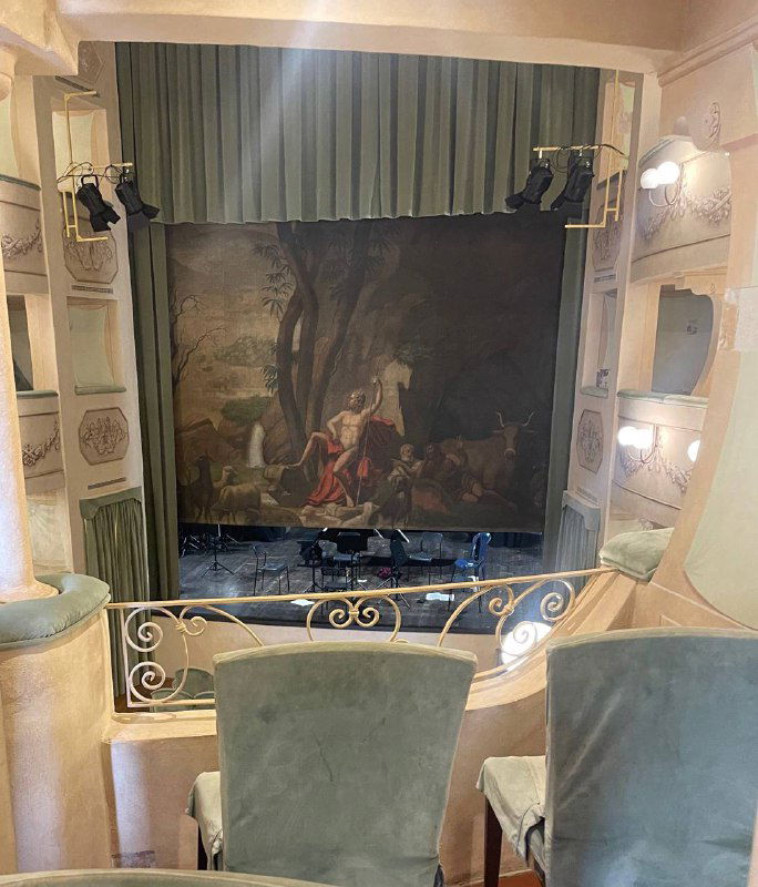 Сцена театра с декоративным занавесом и росписью, вид из ложи на центральный сюжет — исторический театр острова с классической постановкой.