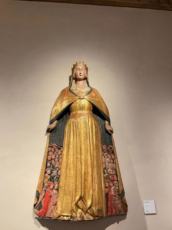 Деревянная или гипсовая статуя святых или мадонны на фоне белой стены в одном из залов Барджелло — религиозная скульптура в экспозиции.