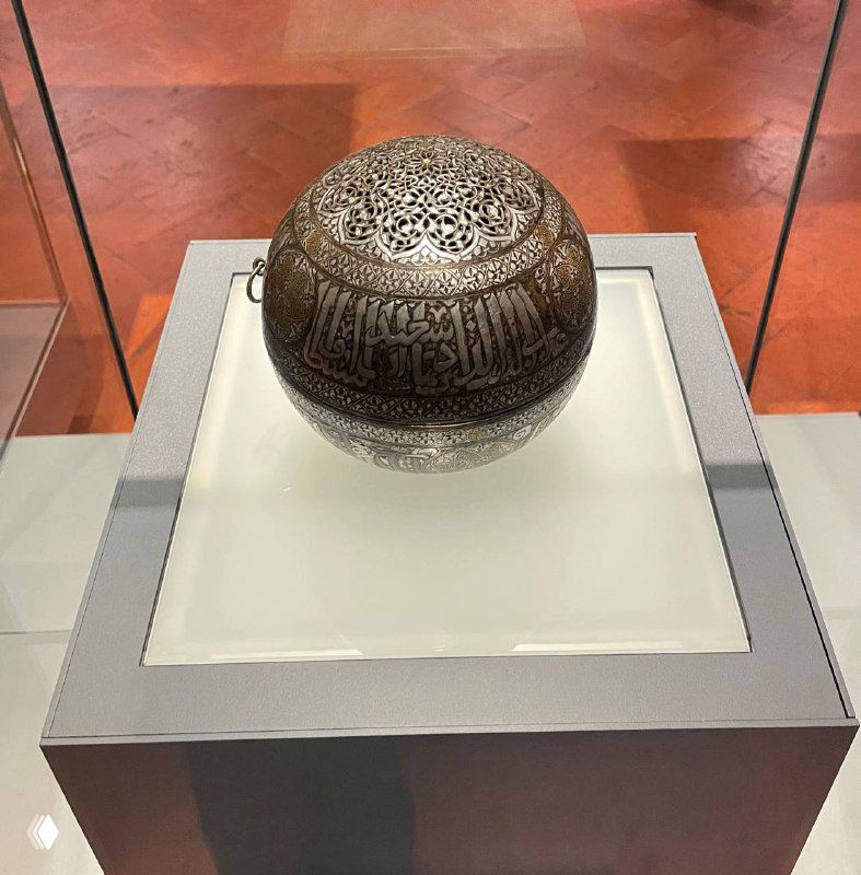 Крупный план металлического резного шаровидного объекта с арабской вязью — пример исламского декоративного искусства в коллекции Барджелло.