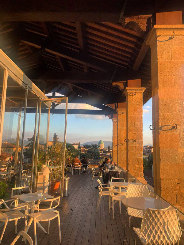 Панорамный вид с крыши музея: открытая терраса с столиками и видом на город и вечерние купола — бар на крыше Museo degli Innocenti.