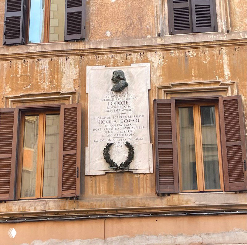 Мемориальная табличка или барельеф на стене исторического здания в Риме между ставнями окна — городские исторические маркеры на фасаде.