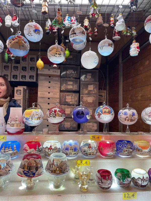 Стеклянные и расписные ёлочные шарики на прилавке: витрина с традиционными рождественскими украшениями и ценниками в евро.