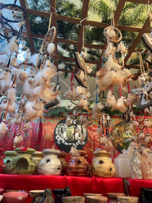 Подвесные украшения с перьями и миниатюрными игрушками: прилавок с легкими декоративными элементами для ёлки и интерьера.