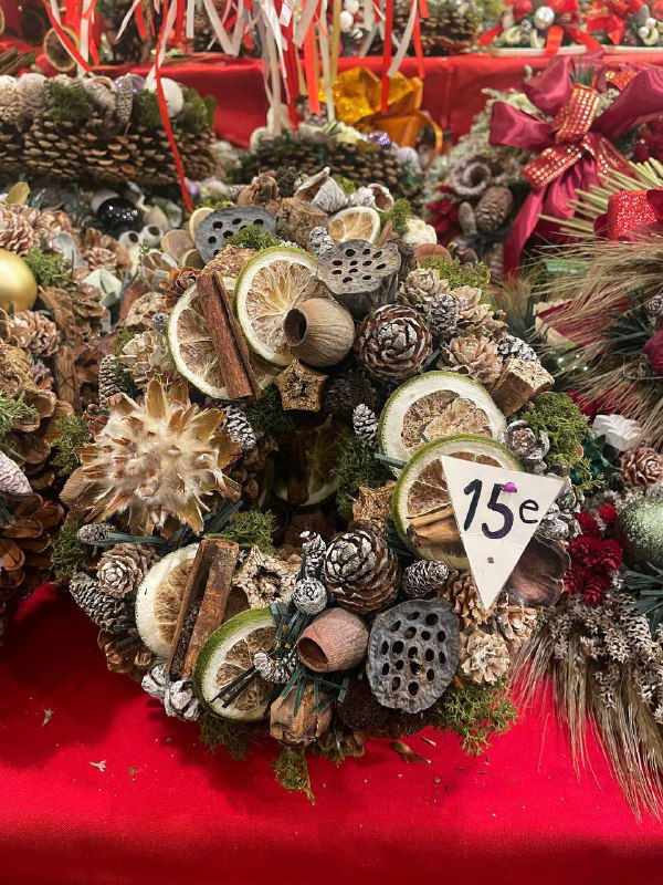 Рождественский венок и натуральные декорации на прилавке с ценой в евро: еловые ветки, сухие фрукты и шишки в праздничном оформлении.