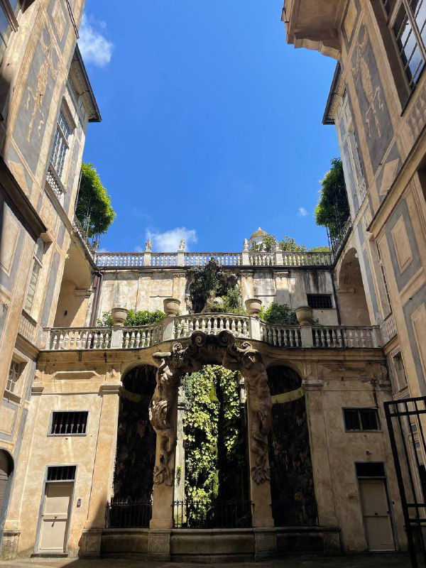 Впечатляющий вход во дворец с аттиком и балюстрадой: каменные ворота и открытое небо над исторической городской резиденцией.