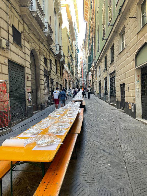 Пешеходная улица с длинными столами и торговыми рядами вдоль фасадов, подготовка уличного маркета или базара в историческом районе.