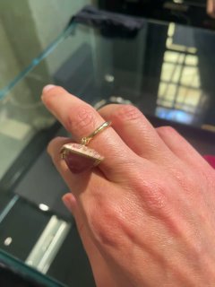 Крупный план пальца с золотым кольцом и витрины ювелирного магазина — демонстрация модели кольца из местного ателье Ness11.