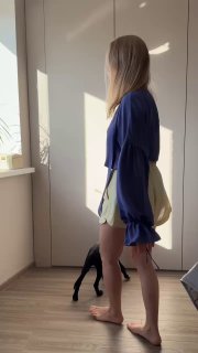 Профиль модели в синей блузке «Стамбул», видно посадку и длину рукава; в кадре солнечный свет и тёмная кошка у ног.