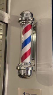 Декоративный классический барбер-полосатый столб на стене салона Otto — визуальный символ парикмахерской, вписанный в музыкальную атмосферу вечера.