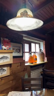 Интерьер аутентичного заведения: деревянная отделка, настольный светильник, бутылки и декор — место напоминает джаз-клуб или местное кафе у озера.