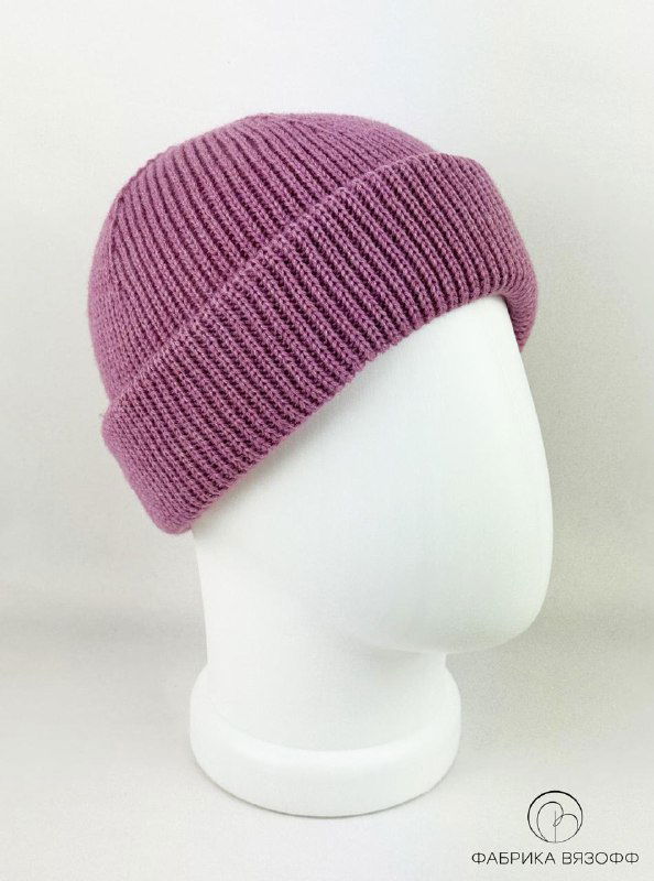 Розовая вязаная шапка на манекене, крупный план; мягкая текстура пряжи и равномерная вязка, светлый фон студии.