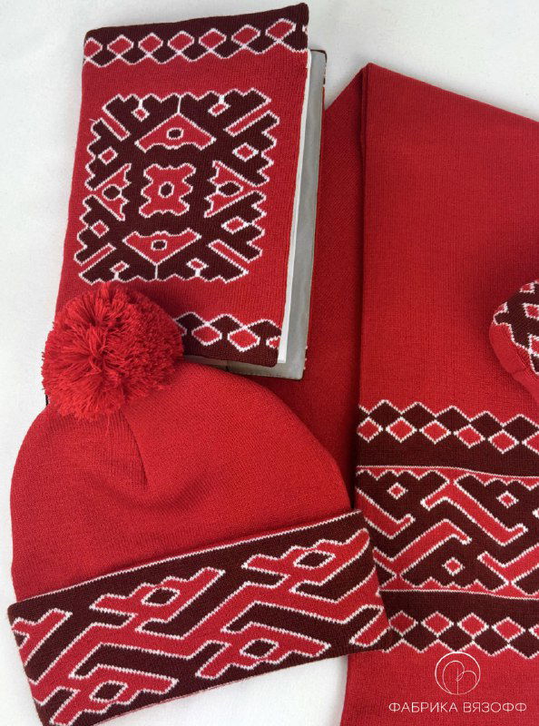 Вид сверху на красный вязаный комплект: обложка, шарф и шапка с характерным национальным орнаментом в едином дизайне.