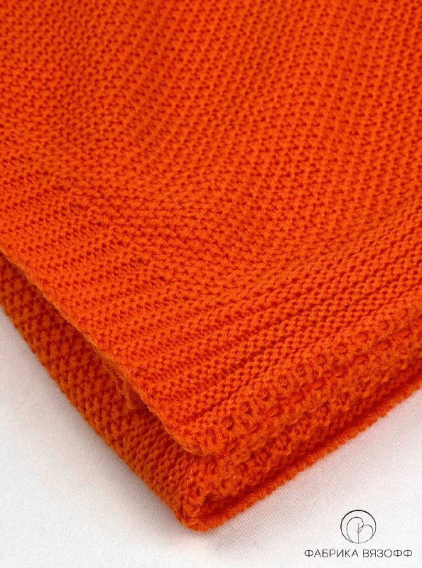Макро-вид кромки оранжевого вязаного пледа: видно рельефное переплетение и аккуратный кант, подчёркивающий качество отделки.
