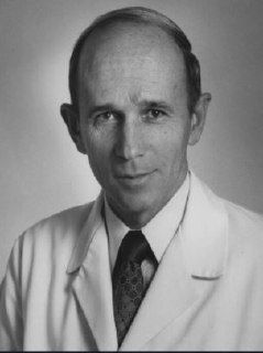 Чёрно‑белый официальный портрет врача-исследователя в костюме и галстуке; строгий академический стиль снимка, ассоциируемый с научной публикацией.