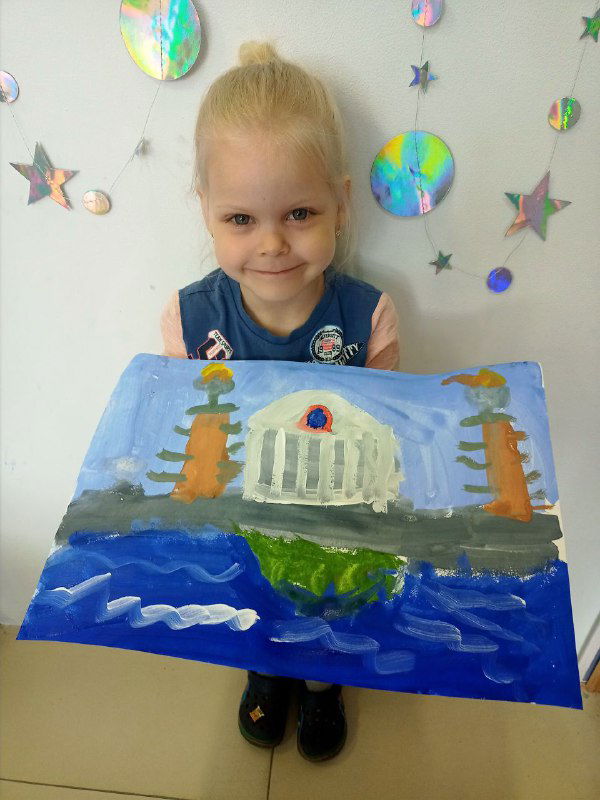 Маленькая ученица держит крупную работу с изображением белого здания и двух колонн у воды; яркие мазки и детская манера письма видны отчётливо.