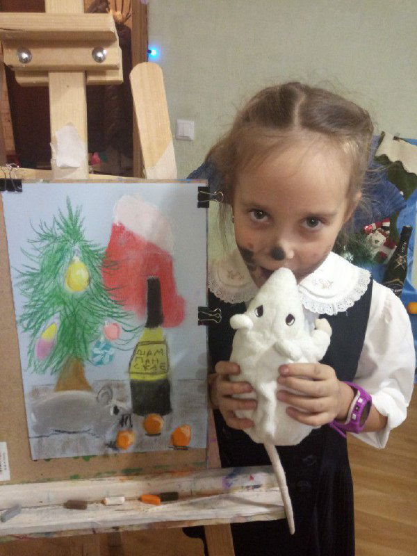 Девочка в школьной форме держит мягкую игрушку на фоне своей рисунка на мольберте; сочетание учебной обстановки и детского творчества.