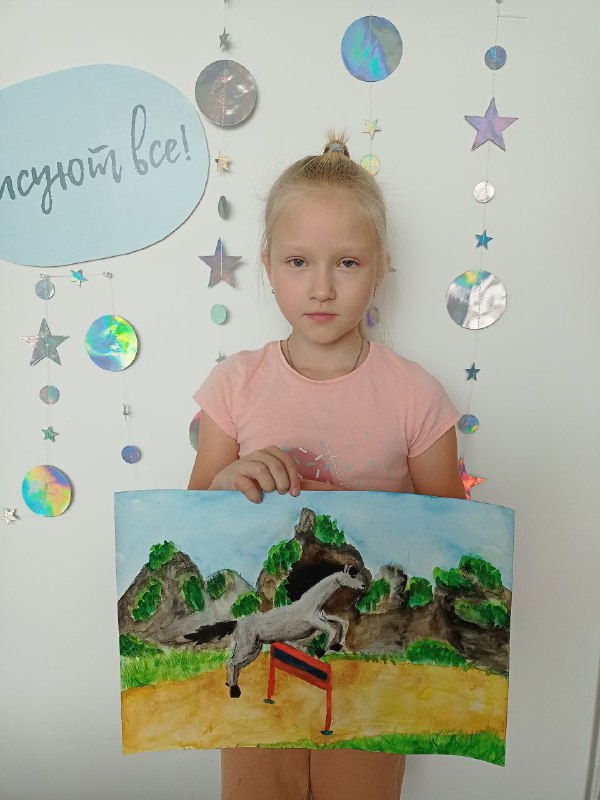 Девочка держит картину с изображением коня на фоне декоративной стены студии, работа демонстрирует уровень начальной школы по рисованию.