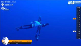 Подводный кадр: фридайвер в синей воде на глубине, рядом страхующий на скутере — момент эвакуации во время соревнований AIDA.