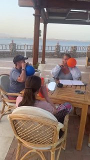 Общий план занятия сзади: несколько слушателей сидят вокруг стола и синхронно используют носодуи, веранда выходит на морской горизонт и пальмы