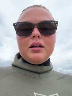 Крупный план автора в гидрокостюме и солнцезащитных очках на фоне пасмурного неба перед стартом соревнований в Сочи.