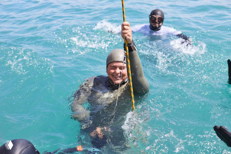 Фридайвер держится за трос и поднимается на поверхность с признаками усталости и удовлетворения после глубокого погружения.