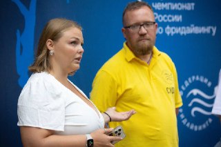 Организатор и представитель организаторов на фоне официального баннера Чемпионата России по фридайвингу, деловая сцена и подготовка мероприятия