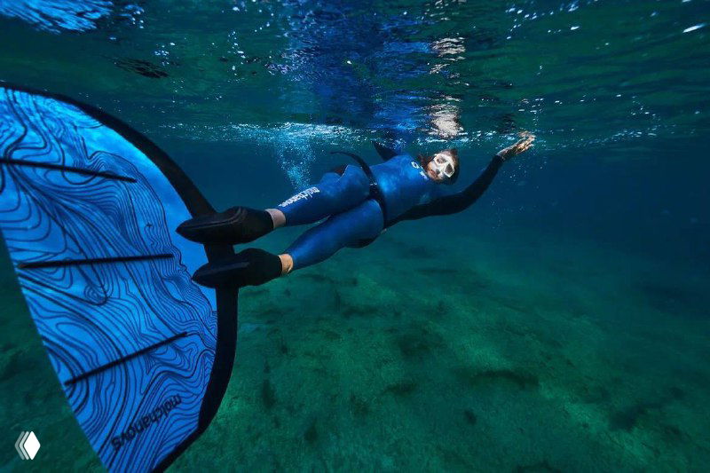 Фридайвер в гидрокостюме с моноластой у поверхности, плавает в прозрачной воде над морским дном; иллюстрация давления при погружении.