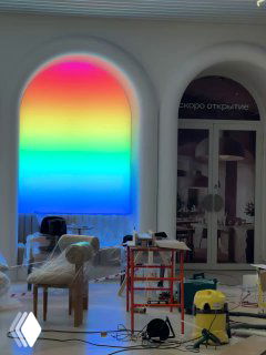 Интерьерный фрагмент с аркой и радужной подсветкой, строительные леса и техника на фоне процесса отделки помещения
