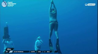 Подводная фотография: фридайвер в вертикальной позе с ластами у буйка на фоне глубокой синей воды и тренировочного снаряжения
