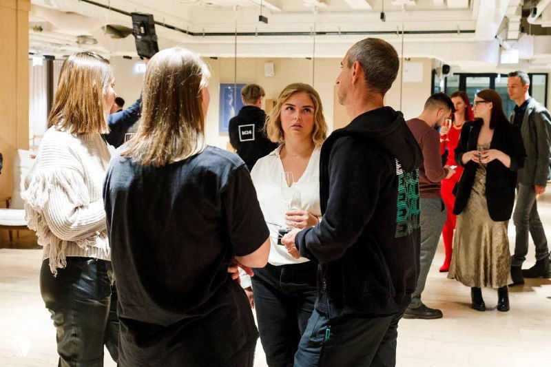 Гости премьеры общаются в фойе мероприятия: Ольга Маркина в окружении коллег и зрителей, неформальные беседы после показа фильма.