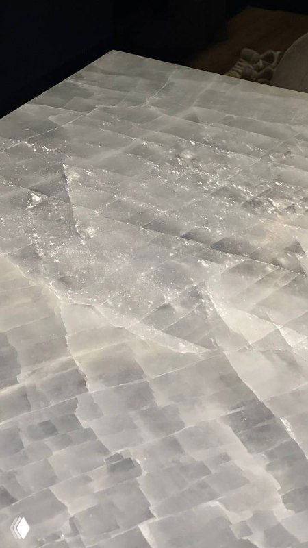 Поверхность ониксовой столешницы под углом, видны кристаллические структуры камня и мягкие отражения света на плоскости.