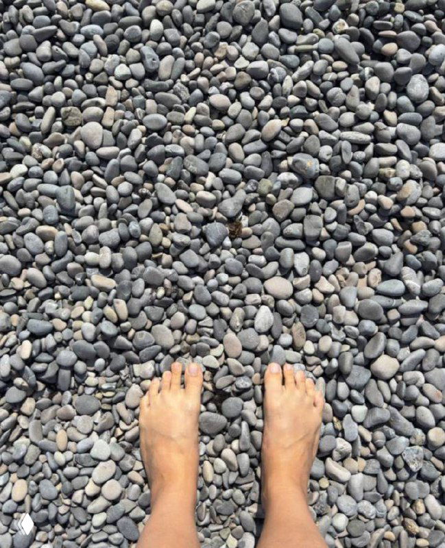 Босые ноги автора на галечном берегу, вид сверху: округлая галька разной формы и текстура, утренний пляж после заплыва и закаливания.