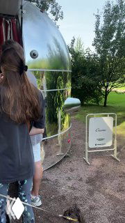 Алюминиевый трейлер джеллатерии Creamo среди зелёной лужайки и деревьев — мобильная точка с вывеской и посетителями в очереди.