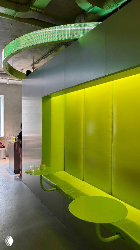 Изогнутый зелёный декоративный элемент и панель в интерьере кофейни 2046, яркий акцент на потолочных конструкциях и мебели.