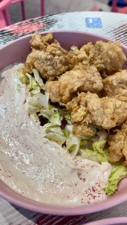 Чаша с панированными кусочками и соусом на дне, сверху листовой салат — кадр жареного филе в панировке на тарелке
