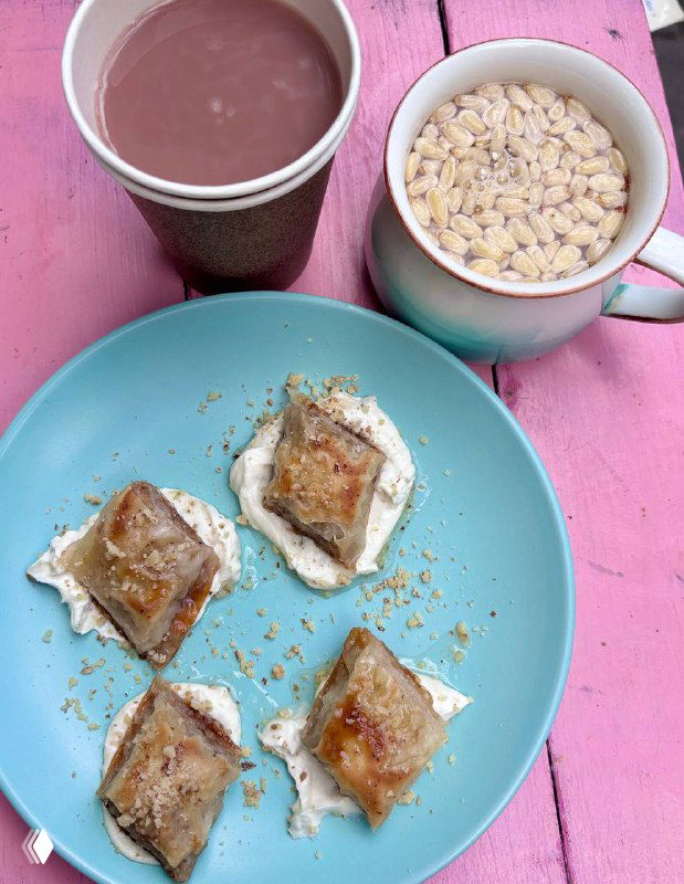 Чашка с горячим какао и кружка с белым кофе рядом с тарелкой с маленькими десертами — тонкая подача на голубой тарелке.