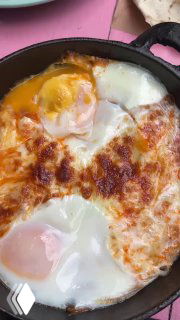 Крупный план шакшуки в другой подаче — запечённые яйца с сыром в сковороде, мягкий желток и золотистая корочка сыра в центре кадра.