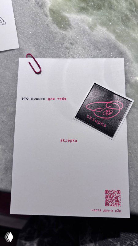 Открыточка и фирменная наклейка Skrepka на белой бумаге: мелкие детали брендинга, бумажная скрепка и аккуратная типографика на столе.
