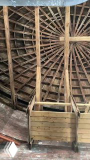 Внутренний каркас овального купола: деревянные балки и конструкция чернового покрытия, вид с галереи под куполом на музейные элементы реставрации.