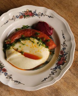 Тёплая тарелка с чоризо, сливочным картофельным пюре и зелёной подачей, видна яркая масляная нотка соуса и аккуратная сервировка