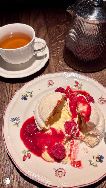 Десертная тарелка с павловой, кукурузным кремом и малиной; сверху видны джем и расплавленный крем — яркие контрасты цветов