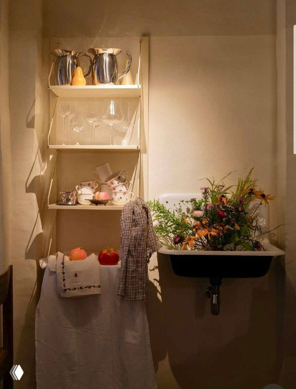 Уютный уголок интерьера с полкой, цветами и раковиной — скандинавский минимализм и текстуры белых тканей в декоре ресторана