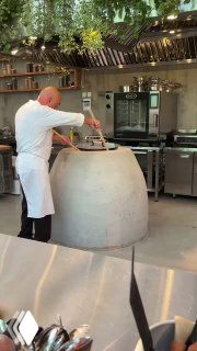 Повар у большого тандыра в открытой пекарне, процесс выпечки шота пури на глазах гостей — работа кухни Bagebi в одноимённом пространстве.