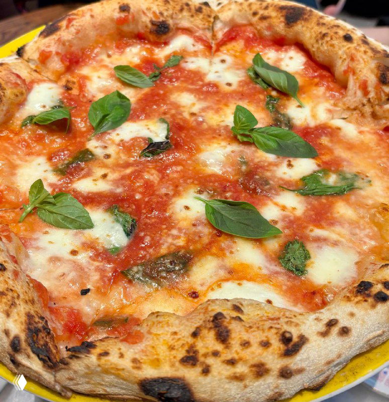 Крупный план пиццы Маргарита с тонким тестом, тянущимся сыром и листьями базилика — вид сбоку и текстура корочки.