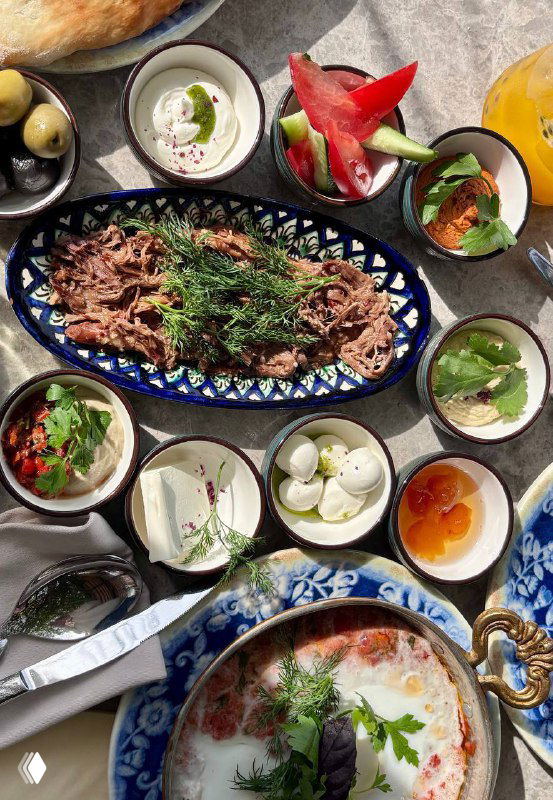 Разнообразный турецкий завтрак на столе в Kilim: множество маленьких закусок, рваная говядина, соусы в керамике, вид сверху в Москве.